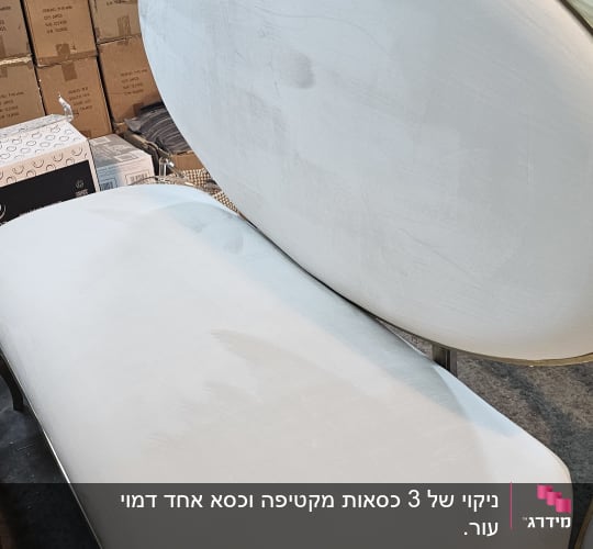 ספה לבנה עם כתמים, קרטונים ברקע
